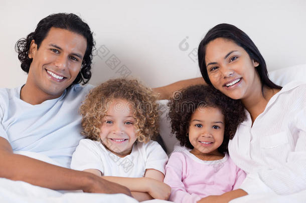 微笑的一家人一起坐在床上