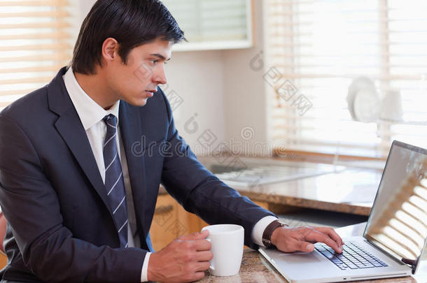 一边喝咖啡一边用笔记本电脑工作的男人