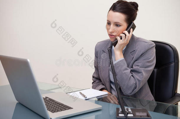 坐在办公桌前打电话的女商人