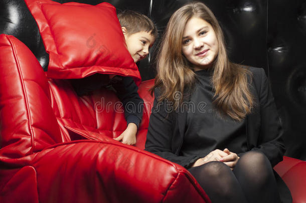坐在红色皮沙发上的小女孩