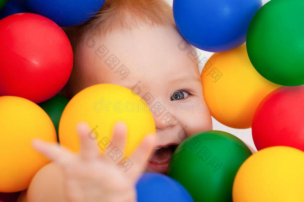微笑的婴儿躺在五颜六色的球中间