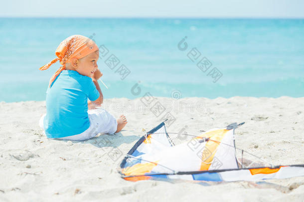可爱的男孩在沙滩上玩一个彩色风筝
