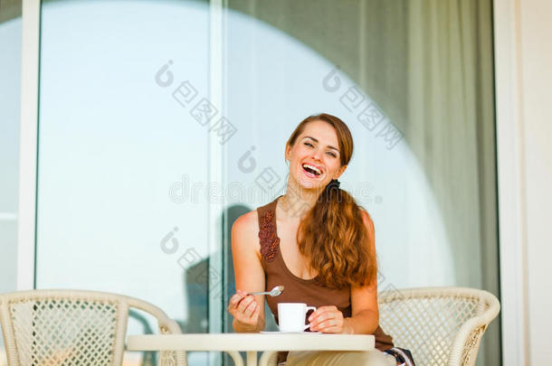 露台上一位微笑的女士正在喝茶