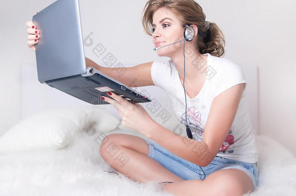 小女孩用银色笔记本电脑和skype耳机