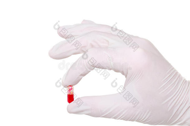 手拿着戴着医用手套的药丸，白色的。