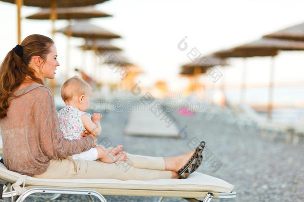 妈妈和宝宝坐在沙滩上晒太阳