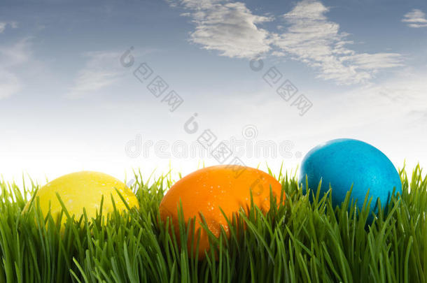 蓝天下草丛中五颜六色的复活节彩蛋
