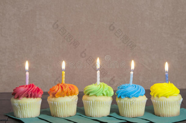 五个明亮的彩色纸杯蛋糕和点燃的蜡烛