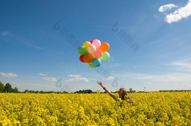 <strong>菜籽油</strong>地上拿着气球的年轻女子。