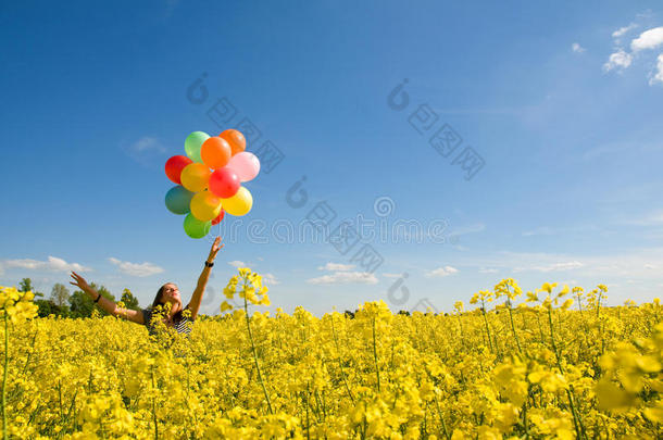 菜籽油地上拿着气球的小女孩。
