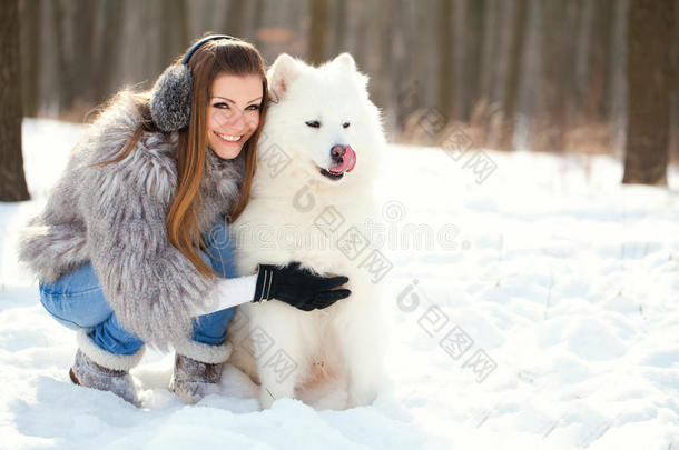 冬季森林里养着狗的时尚女郎萨莫耶德