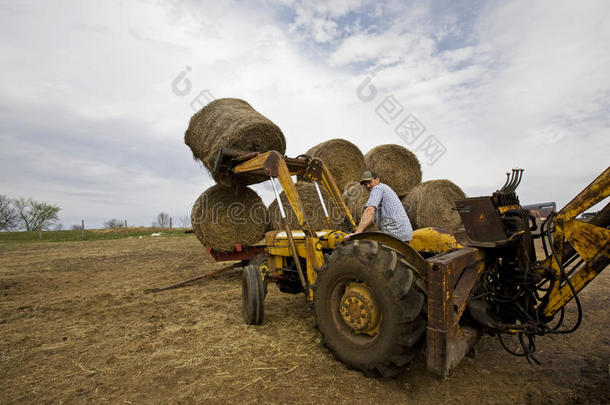 快乐<strong>的</strong>农场主在拖拉机上打<strong>圆圆的</strong>干草包