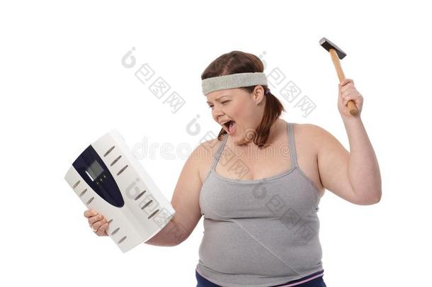 愤怒的胖女人拿着锤子和秤