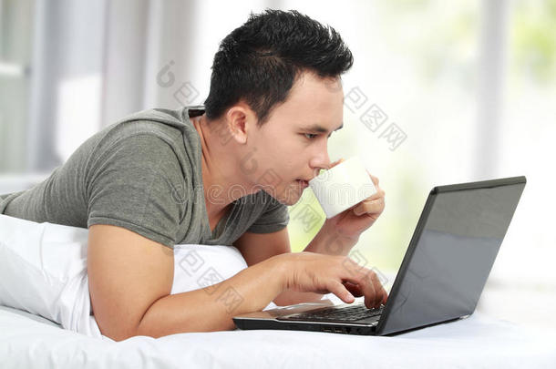 躺在床上用笔记本电脑的男人