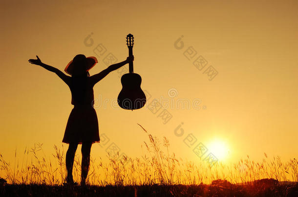 日落剪影的快乐女人和吉他