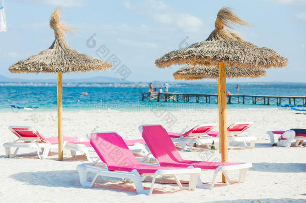 沙滩上有两把椅子和雨伞。