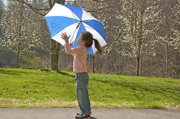 在<strong>刮风</strong>天玩伞的小女孩。