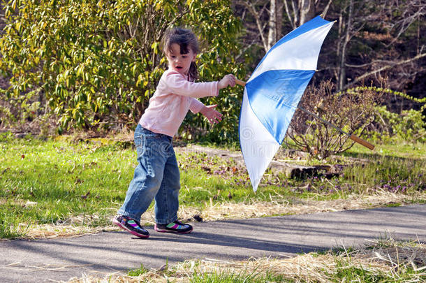 在刮风天玩伞的小女孩。