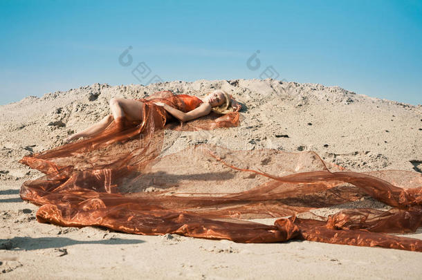 穿着<strong>橘色</strong>布躺在沙滩上的女孩