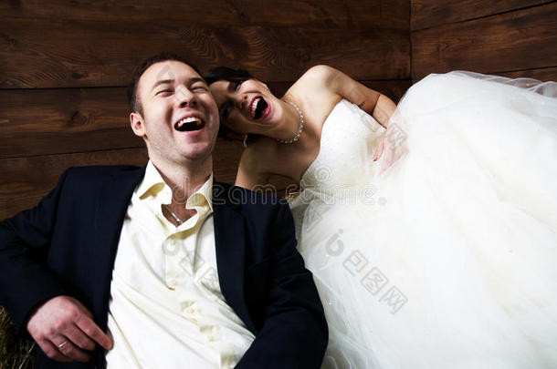 一对穿着婚纱的夫妇在谷仓里大笑