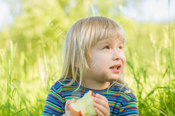 可爱的宝宝坐在草地上吃红苹果