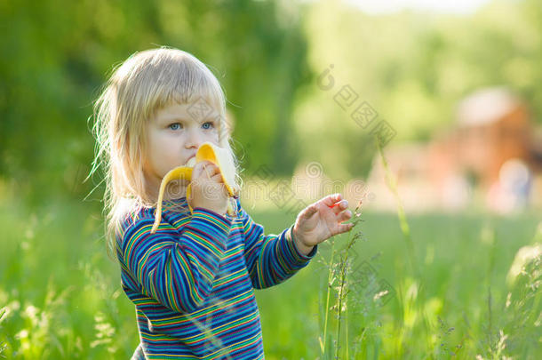 可爱的宝宝吃香蕉呆在高高的草地上
