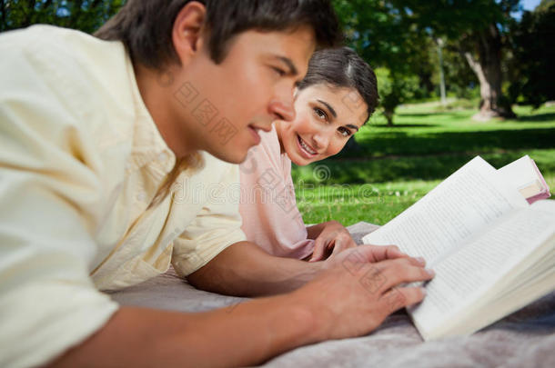 一个女人和朋友在公园里看书时<strong>侧身</strong>看