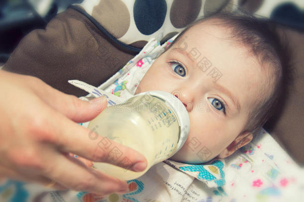 可爱的七个月大的宝宝用奶瓶吃饭