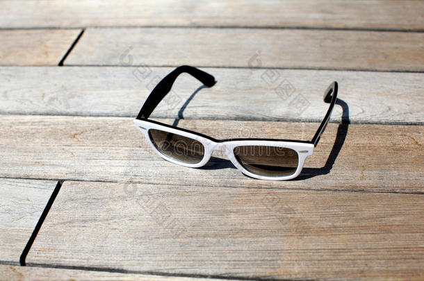 太阳眼镜放在木制甲板上，阳光充足