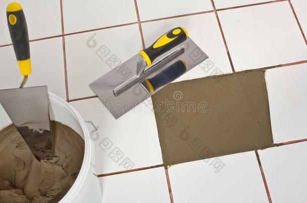 用泥刀修补旧的白瓷砖地板