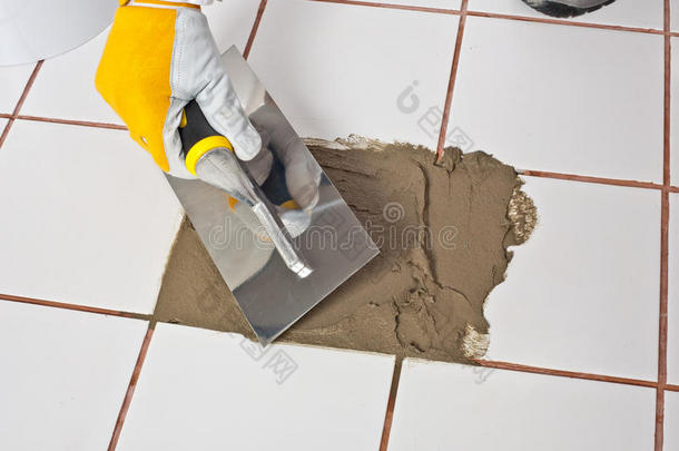 用泥刀手工修补旧的白瓷砖地板