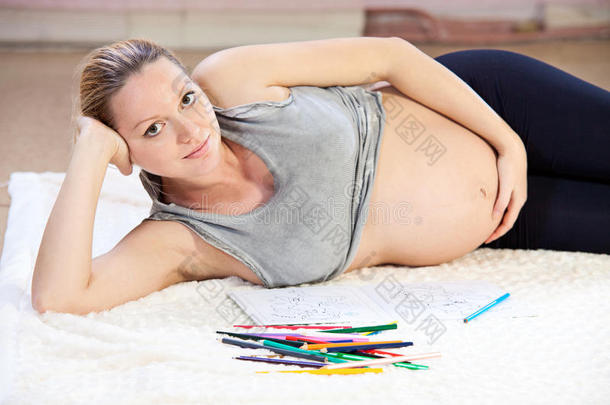 漂亮的年轻孕妇用铅笔画画