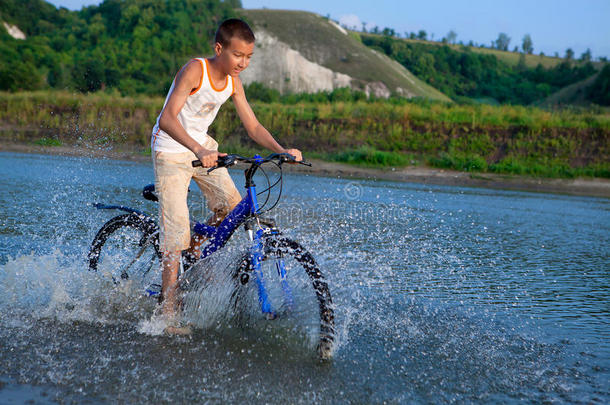 男孩骑自行车沿河而行