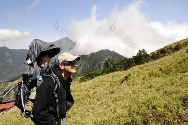 快乐的父亲背着孩子在背包里，山上