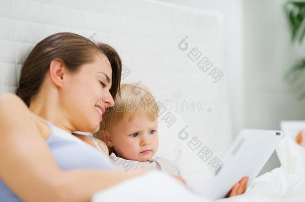 年轻妈妈在平板电脑上<strong>给宝宝</strong>看东西