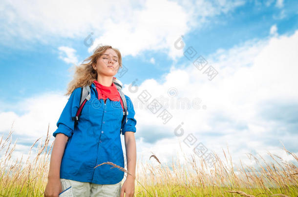 年轻的旅游妇女在夏日的田野里放松。