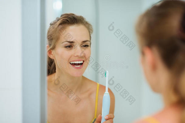 快乐女人在浴室用<strong>电动牙刷</strong>