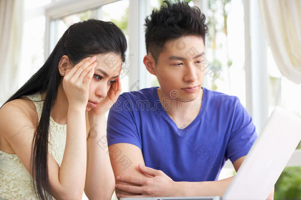 忧心忡忡的中国年轻夫妇使用笔记本电脑