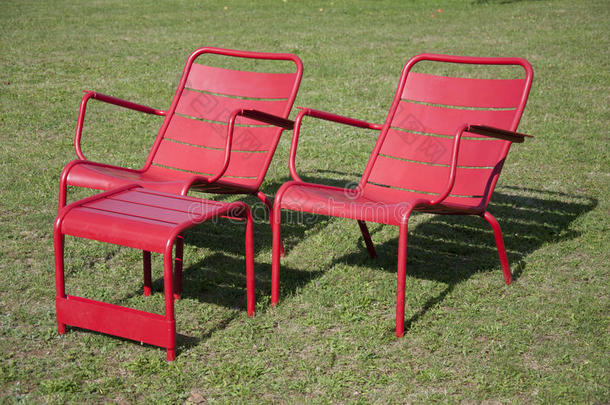 两张红色的椅子和一张红色的桌子在正午的阳光下