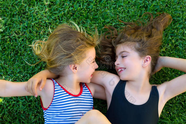 姐妹小女孩微笑着躺在花园的草地上