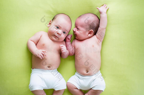 有趣的双胞胎兄弟婴儿躺在草地上