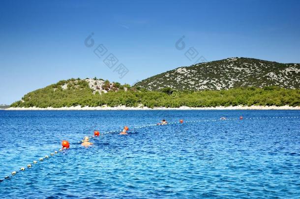 克罗地亚达尔马提亚，人们带着浮标在干净温暖的海洋中游泳