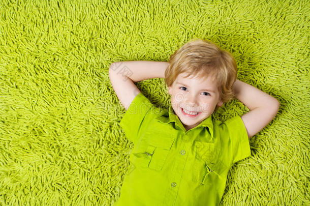 快乐的孩子躺在<strong>绿地毯</strong>的背景上