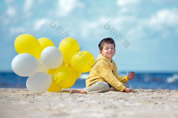海滩上有气球的可爱小男孩