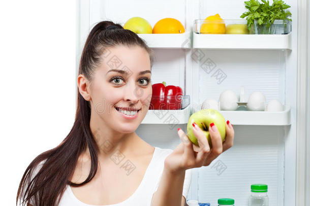 可爱的女孩，苹果在打开的冰箱附近