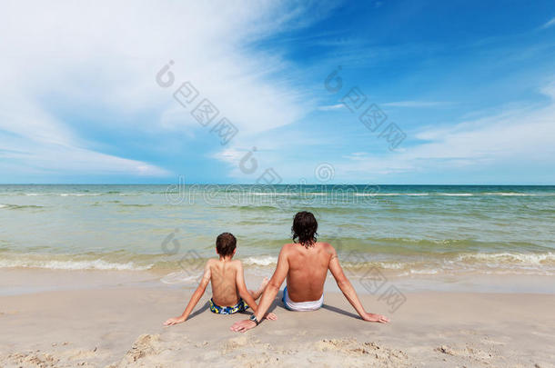 坐在沙滩上的父子。