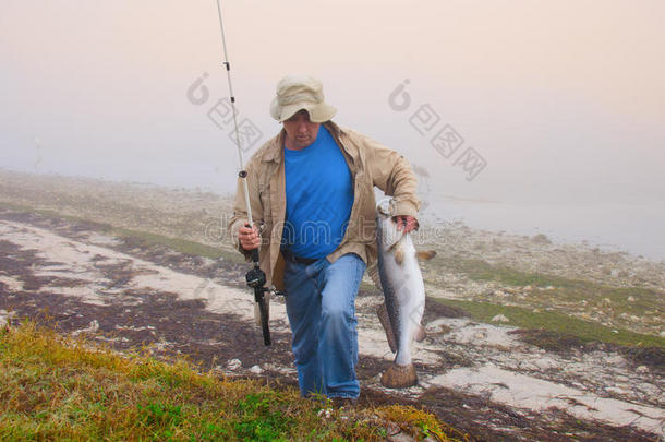 渔夫在一个雾蒙蒙的早晨带着一条大鱼