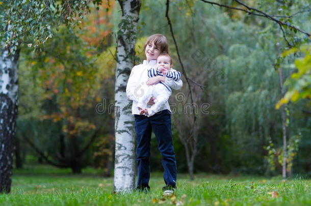 抱着妹妹站在树下的男孩