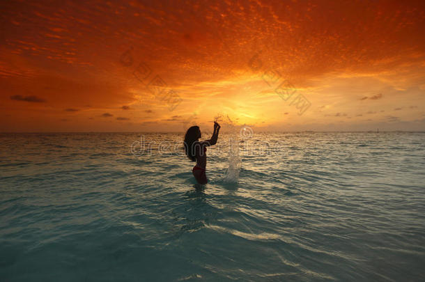 日落时在海里<strong>溅水</strong>的女人