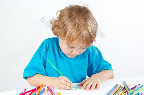 可爱的小男孩用彩色铅笔在白色背景上画画